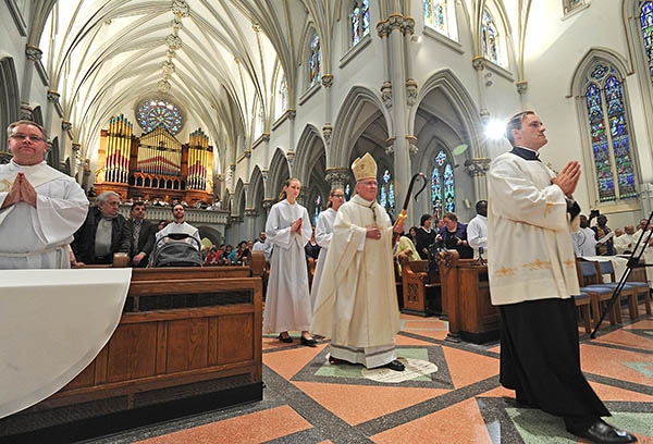 As they prepare to be ordained, candidates Martin Gallagher (far left) and Luke Uebler (center left) pray as Master of Ceremonies Father Ryszard S. Biernat and Bishop Richard Malone head towards the altar. (Dan Cappellazzo/Staff Photographer)